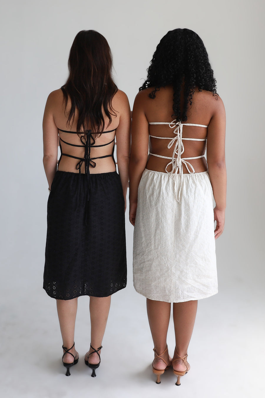 Two models showing the back of dresses.
