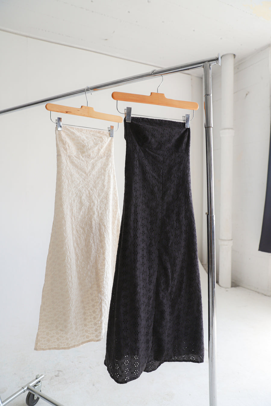 Two dresses hanging on a clothing rack.