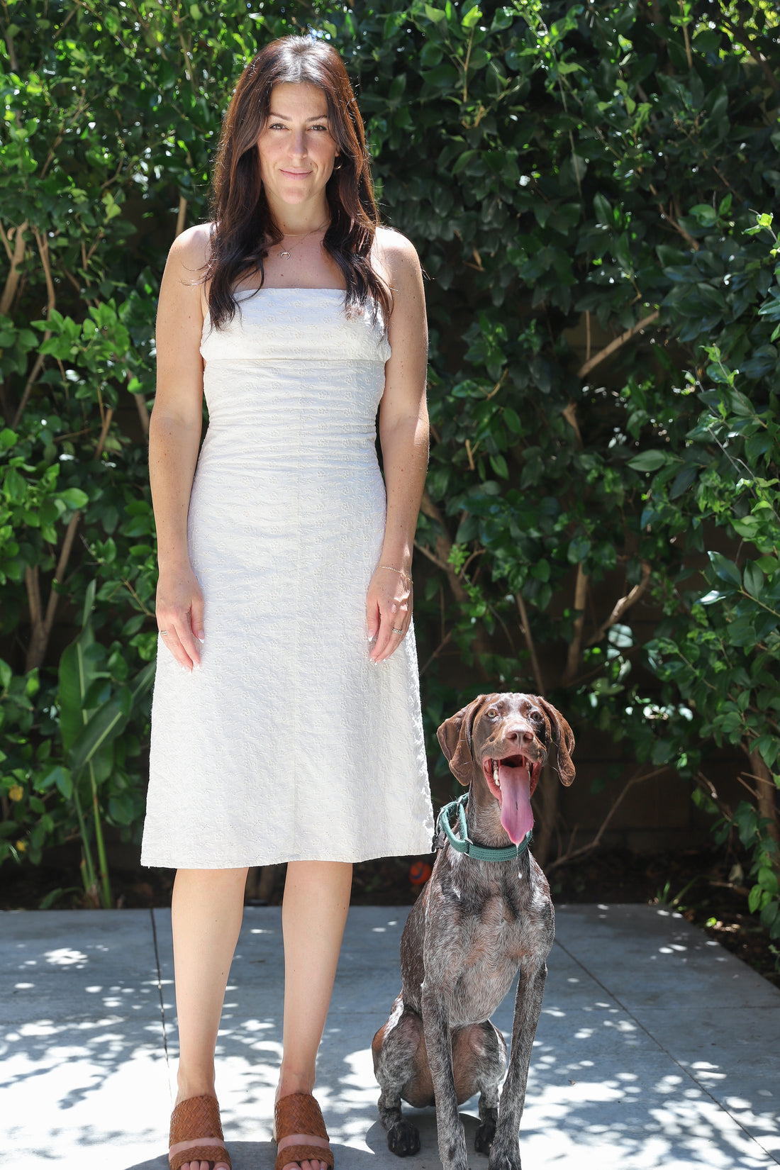 Model standing up straight facing the camera next to a dog.
