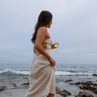 Model at the beach holding a wine glass.